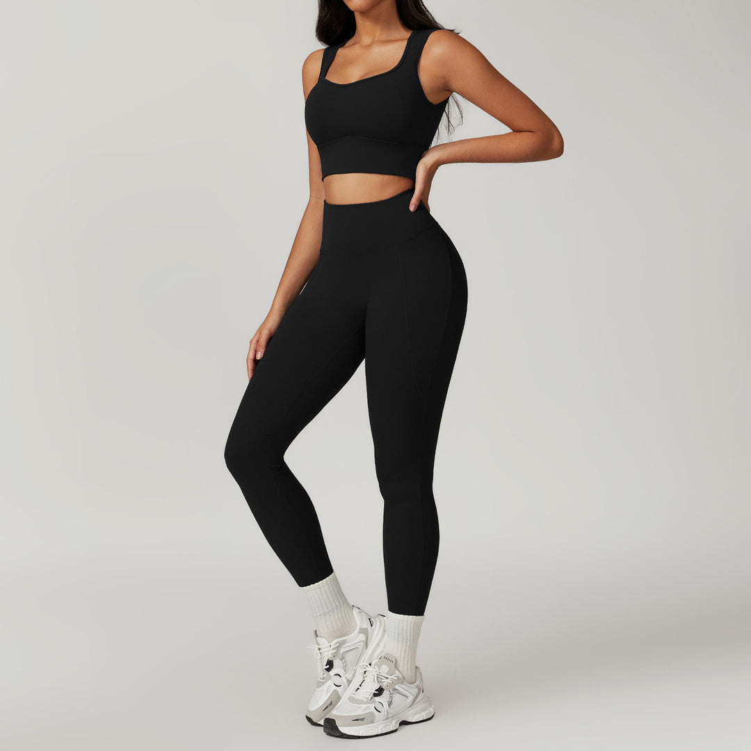 Person wearing a black athletic outfit with white sneakers on a gray background