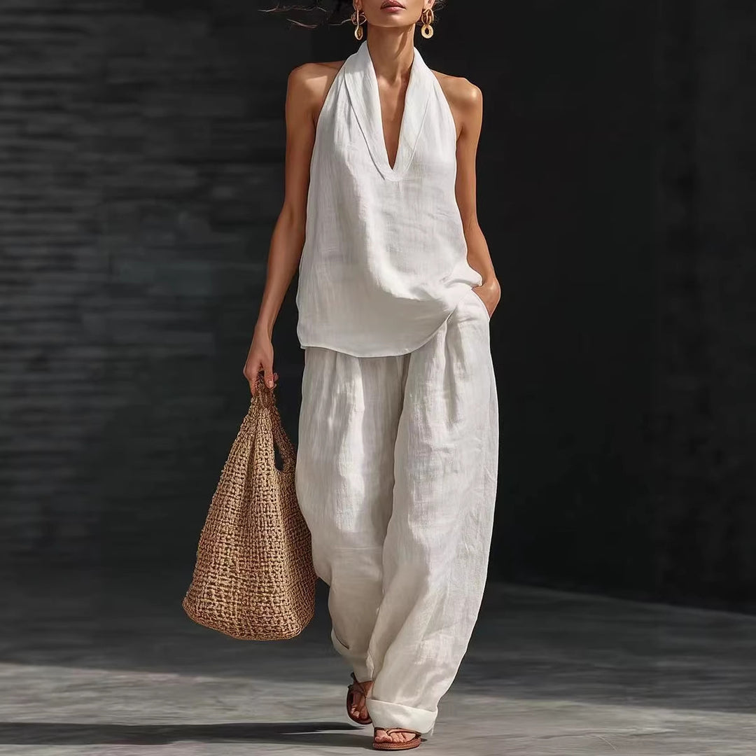 Woman in a white outfit holding a woven bag against a dark background