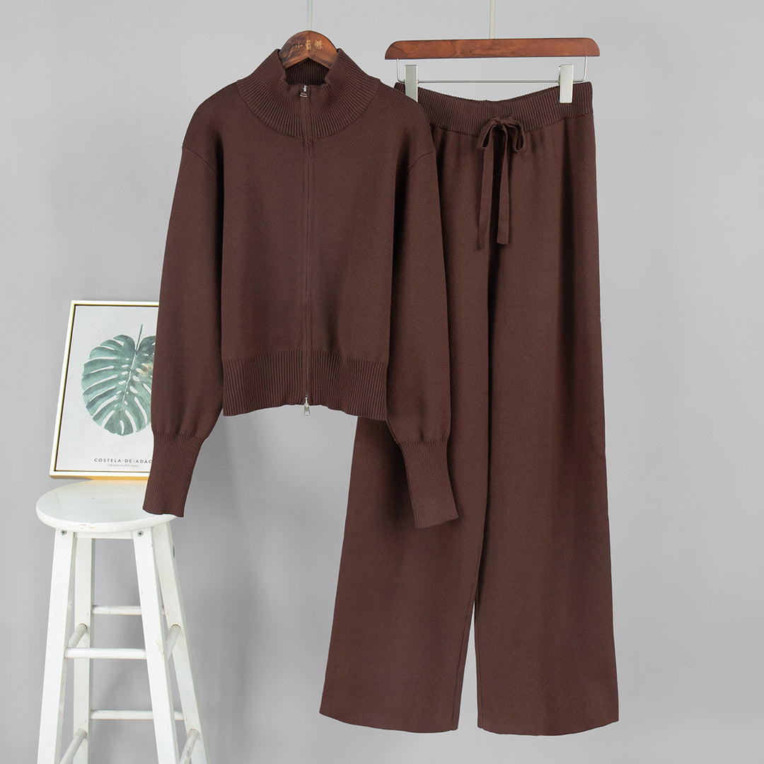 Brown sweater and pants set on hangers against a gray background