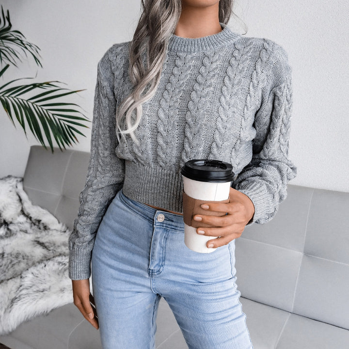 Person wearing a gray cable knit sweater and light blue jeans, holding a coffee cup.