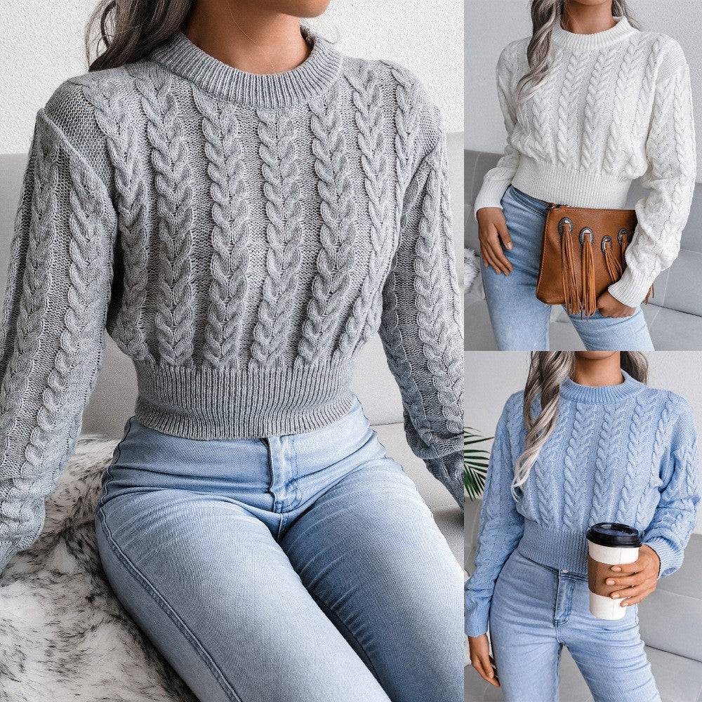 Woman wearing a gray cable knit sweater and light blue jeans, holding a brown bag.