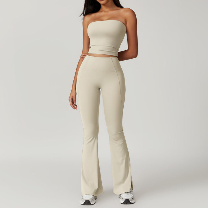Woman wearing a beige strapless top and flared pants on a plain background