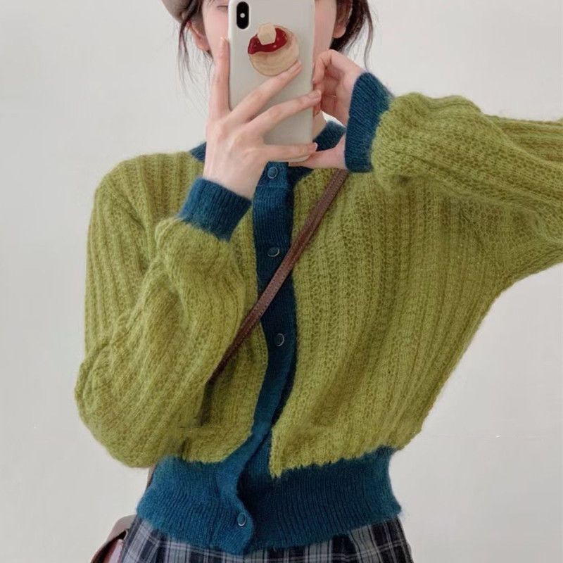 Person wearing a green and blue knitted cardigan taking a selfie.