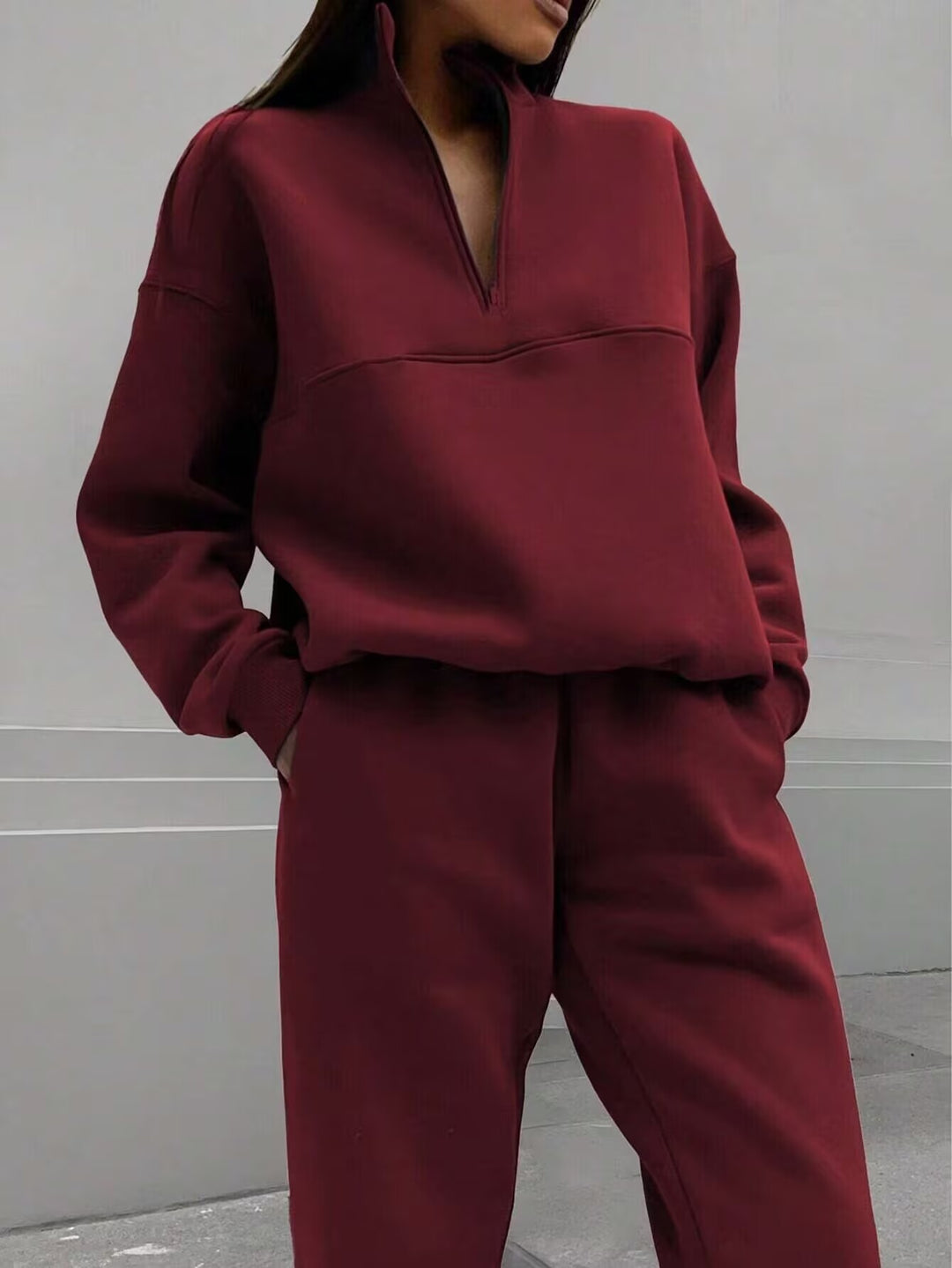 Maroon tracksuit worn by a person against a neutral background