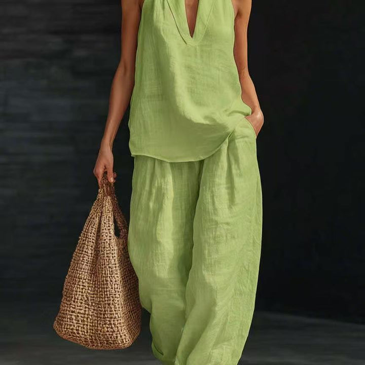 Person wearing a green outfit holding a woven bag against a dark background