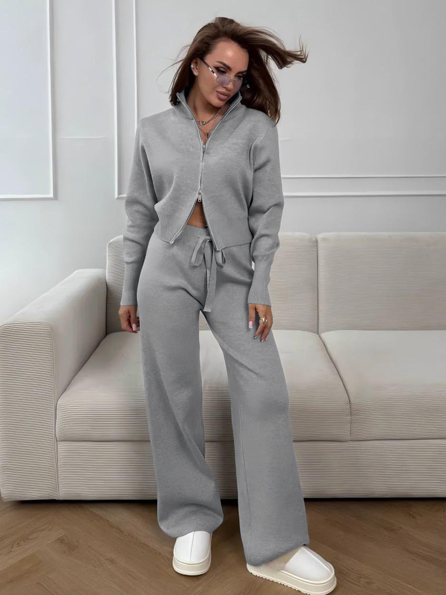 Woman in a gray tracksuit standing in a modern living room.