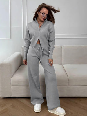 Woman in a gray tracksuit standing in a modern living room.