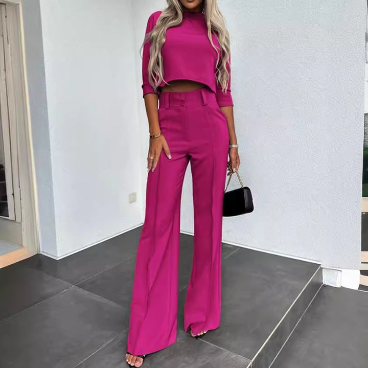 Woman wearing a bright pink outfit with high-waisted pants and top, standing indoors.