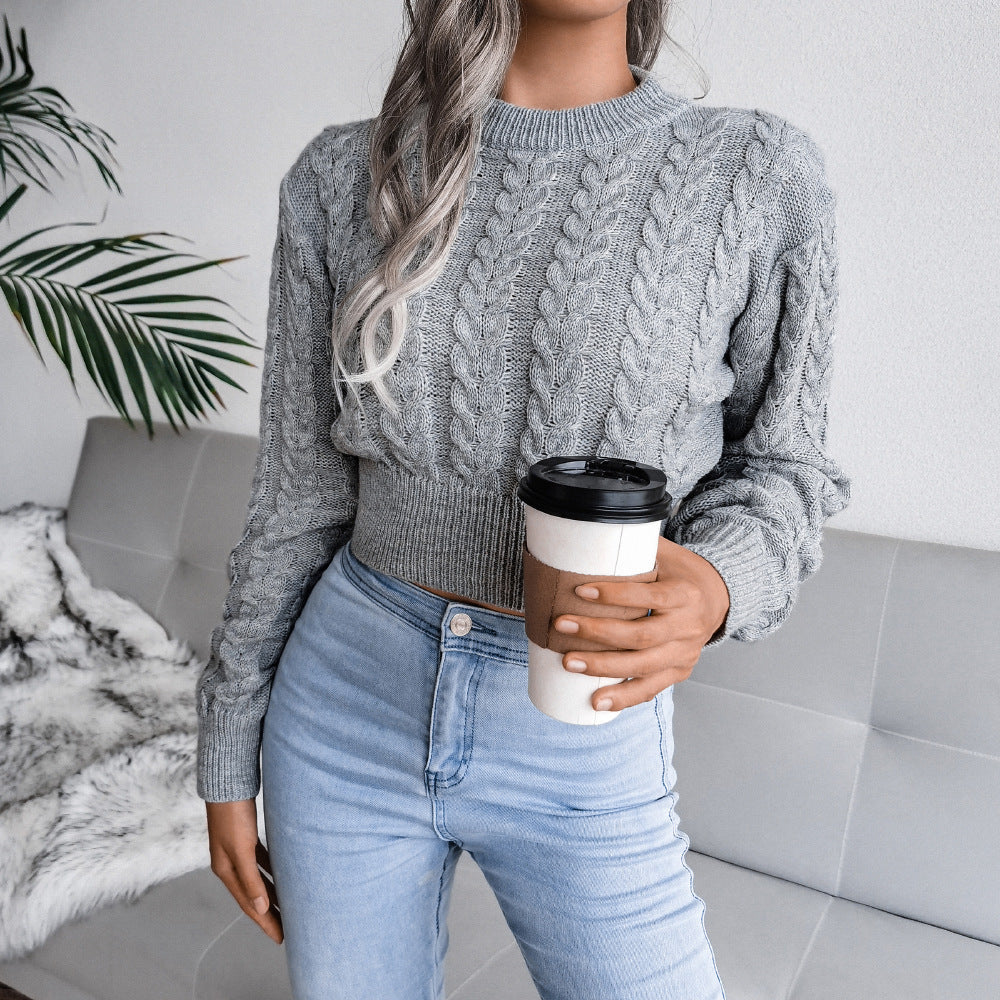 Person wearing a gray cable knit sweater and light blue jeans, holding a coffee cup.