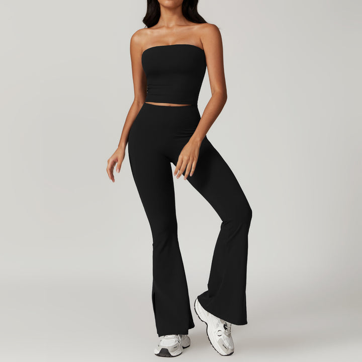 Person wearing a black strapless top and high-waisted pants with white sneakers on a light gray background