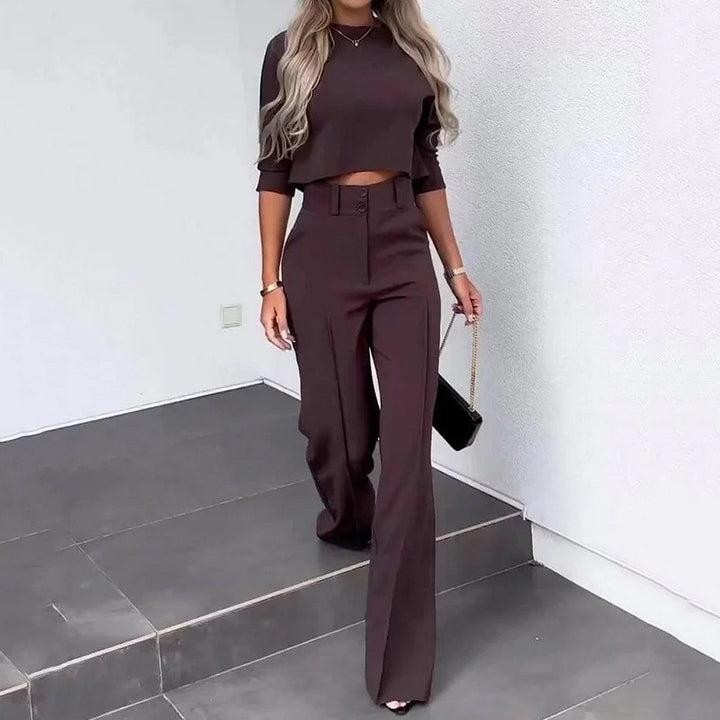 Woman in a brown outfit standing on a staircase with a white wall background