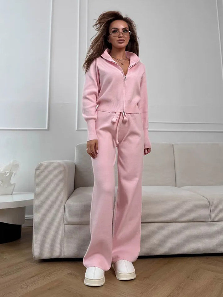 Woman wearing a pink tracksuit standing in a modern living room.