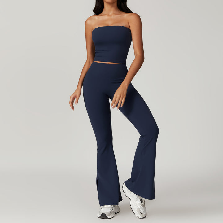 Woman wearing a navy strapless top and pants with white sneakers on a light gray background