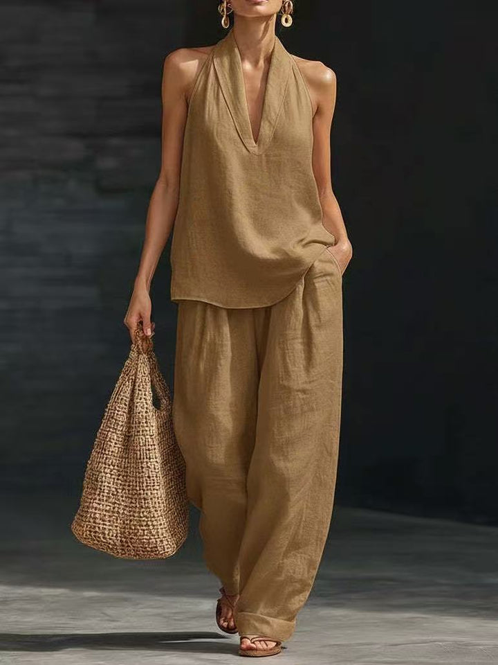 Woman in beige linen outfit holding a woven bag against a dark background