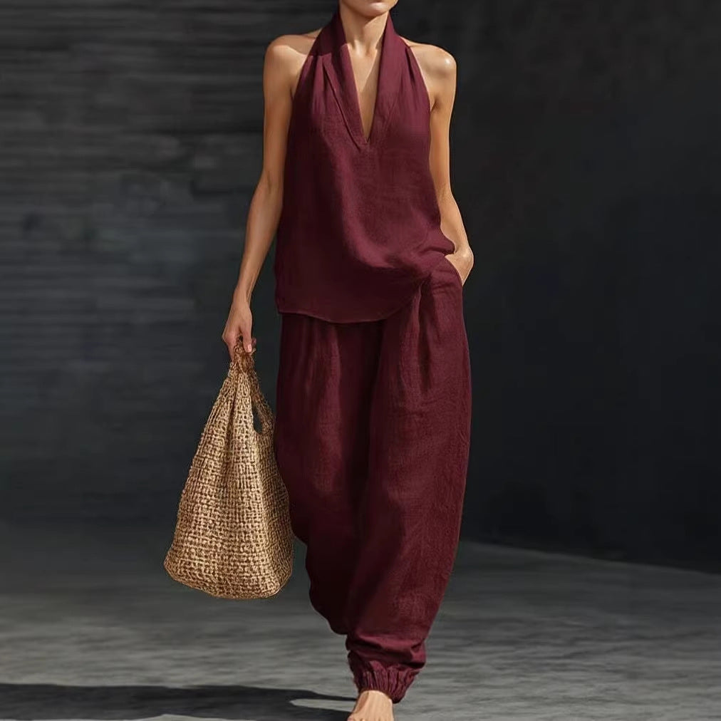 Person wearing a burgundy outfit holding a woven bag against a dark background