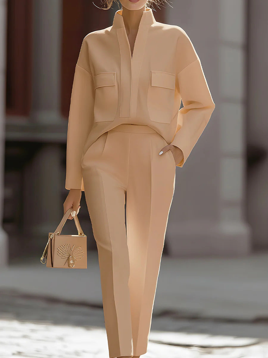 Person wearing a beige outfit with a matching handbag in an urban setting