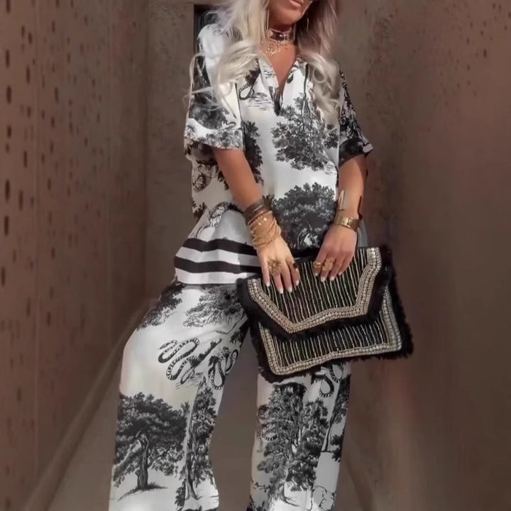 Person wearing a black and white patterned outfit holding a black clutch.