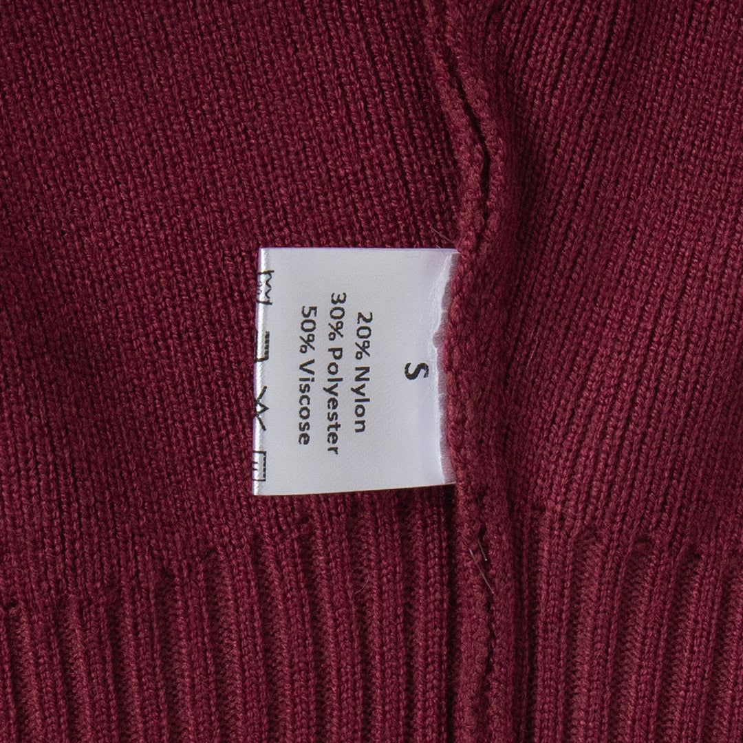 Close-up of a fabric label on a maroon sweater with text details.