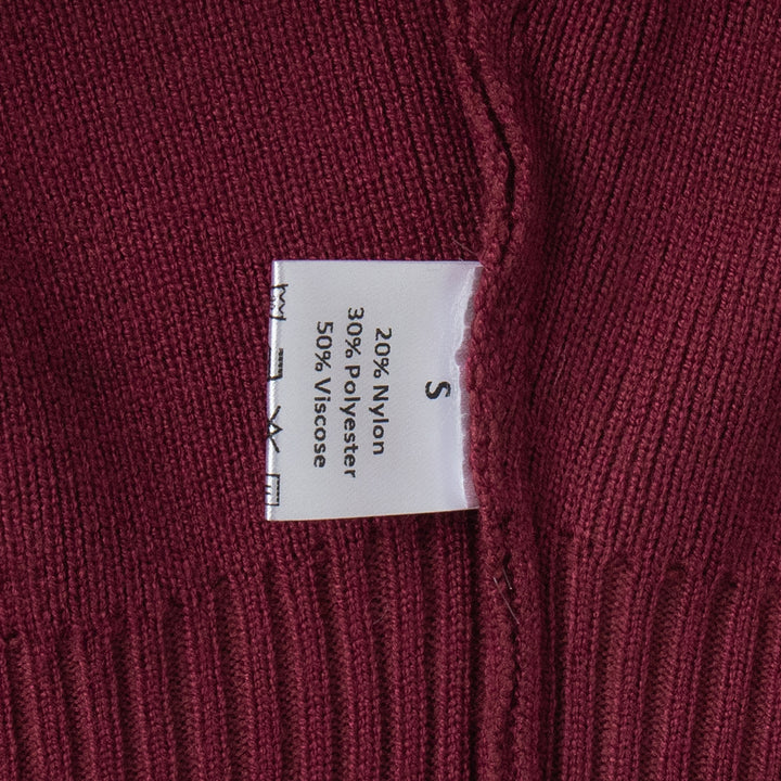 Close-up of a fabric label on a maroon sweater with text details.