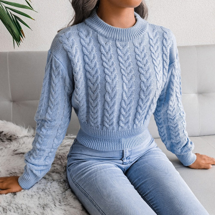 Person wearing a light blue cable knit sweater and jeans sitting on a couch.