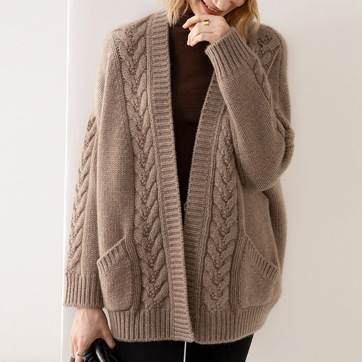 Person wearing a brown cable knit cardigan against a white background