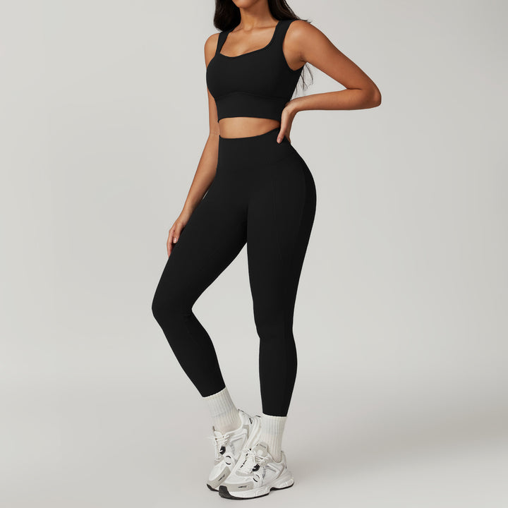 Person wearing a black athletic outfit with white sneakers on a gray background