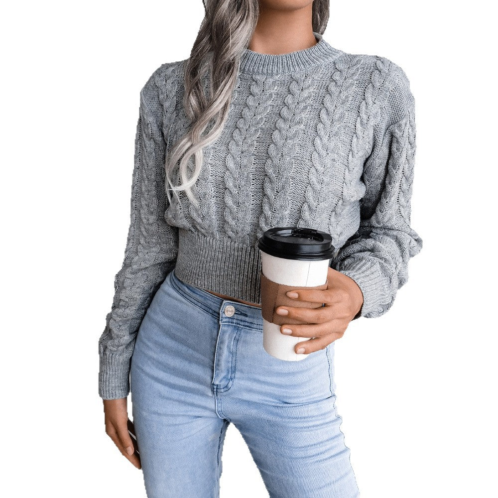 Person wearing a gray cable knit sweater and light blue jeans, holding a coffee cup.
