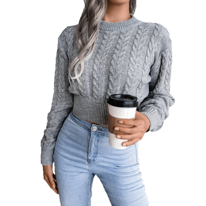 Person wearing a gray cable knit sweater and light blue jeans, holding a coffee cup.