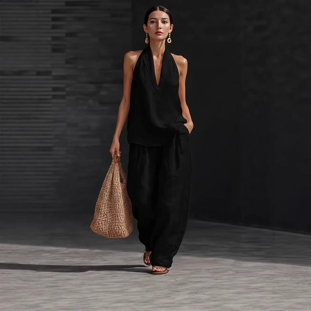 Woman in a black outfit holding a woven bag against a dark background