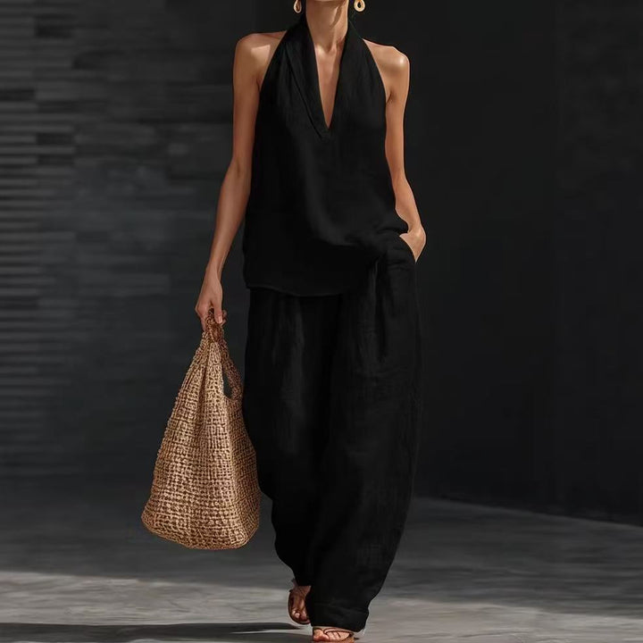 Woman in black outfit holding a woven bag against a dark background