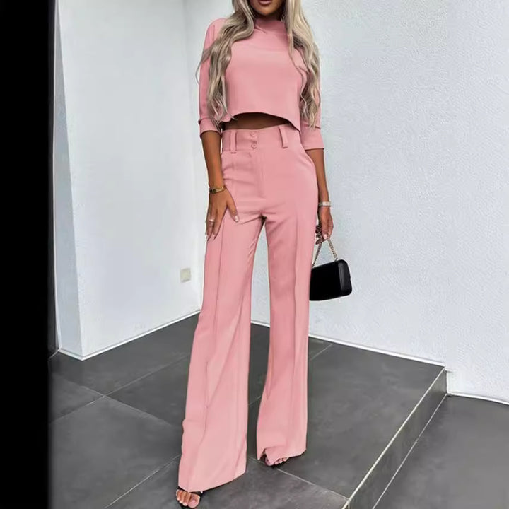 Woman wearing a pink outfit with wide-leg pants in a minimalistic setting