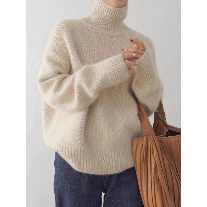 Person wearing a beige sweater holding a brown bag against a white background