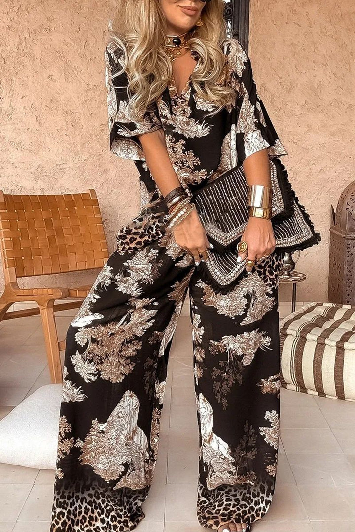 Woman in a black and white floral outfit holding a clutch in an indoor setting.