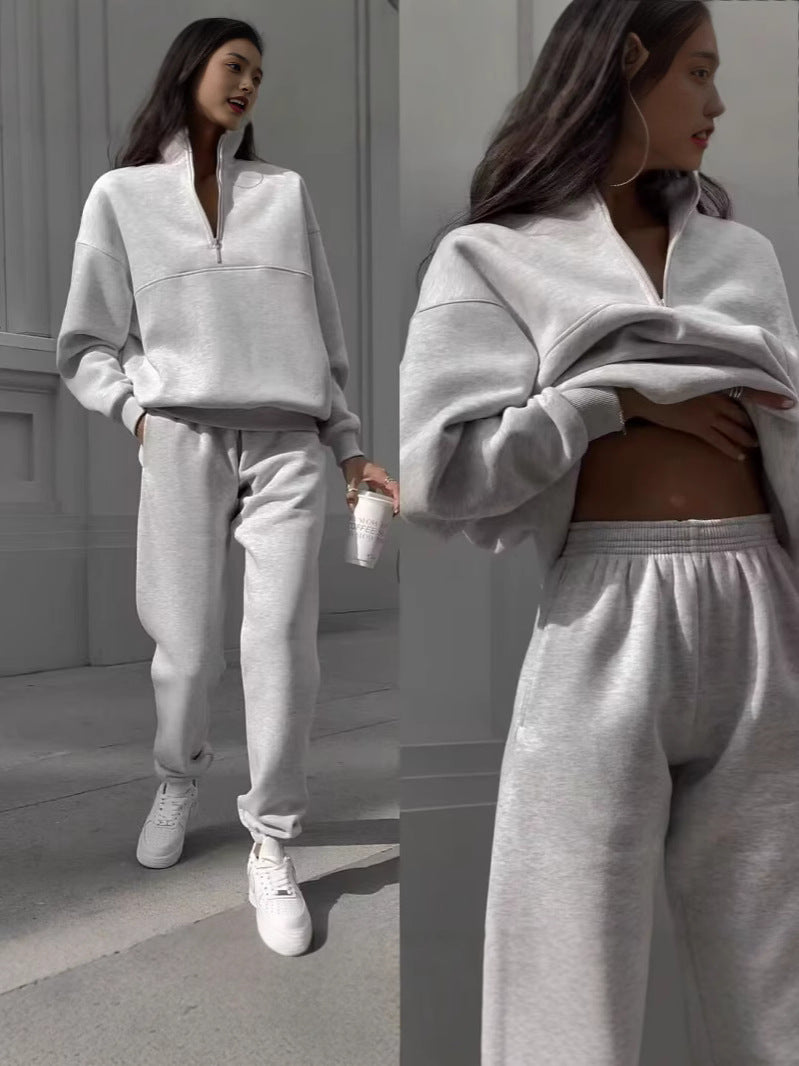 Woman wearing a gray tracksuit standing against a neutral background