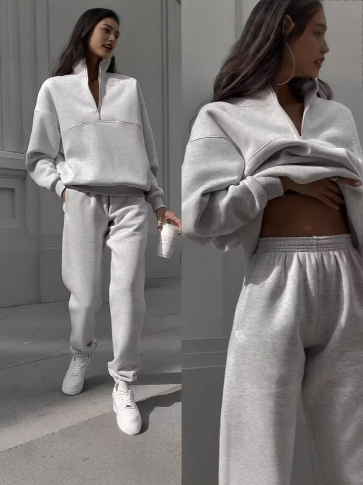 Woman wearing a gray tracksuit standing against a neutral background