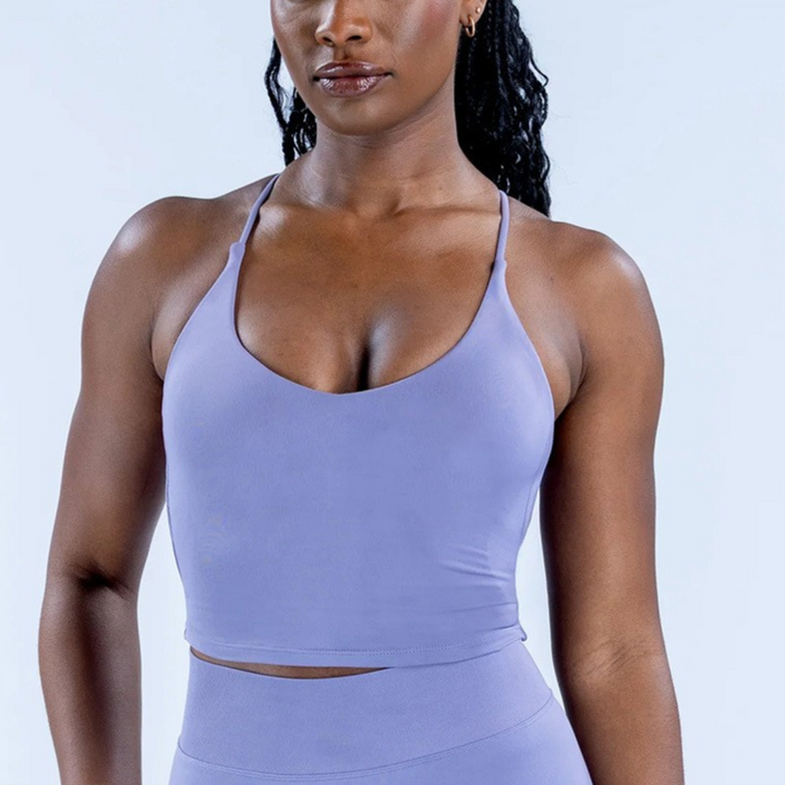 Woman wearing a light purple sports bra and leggings on a light blue background