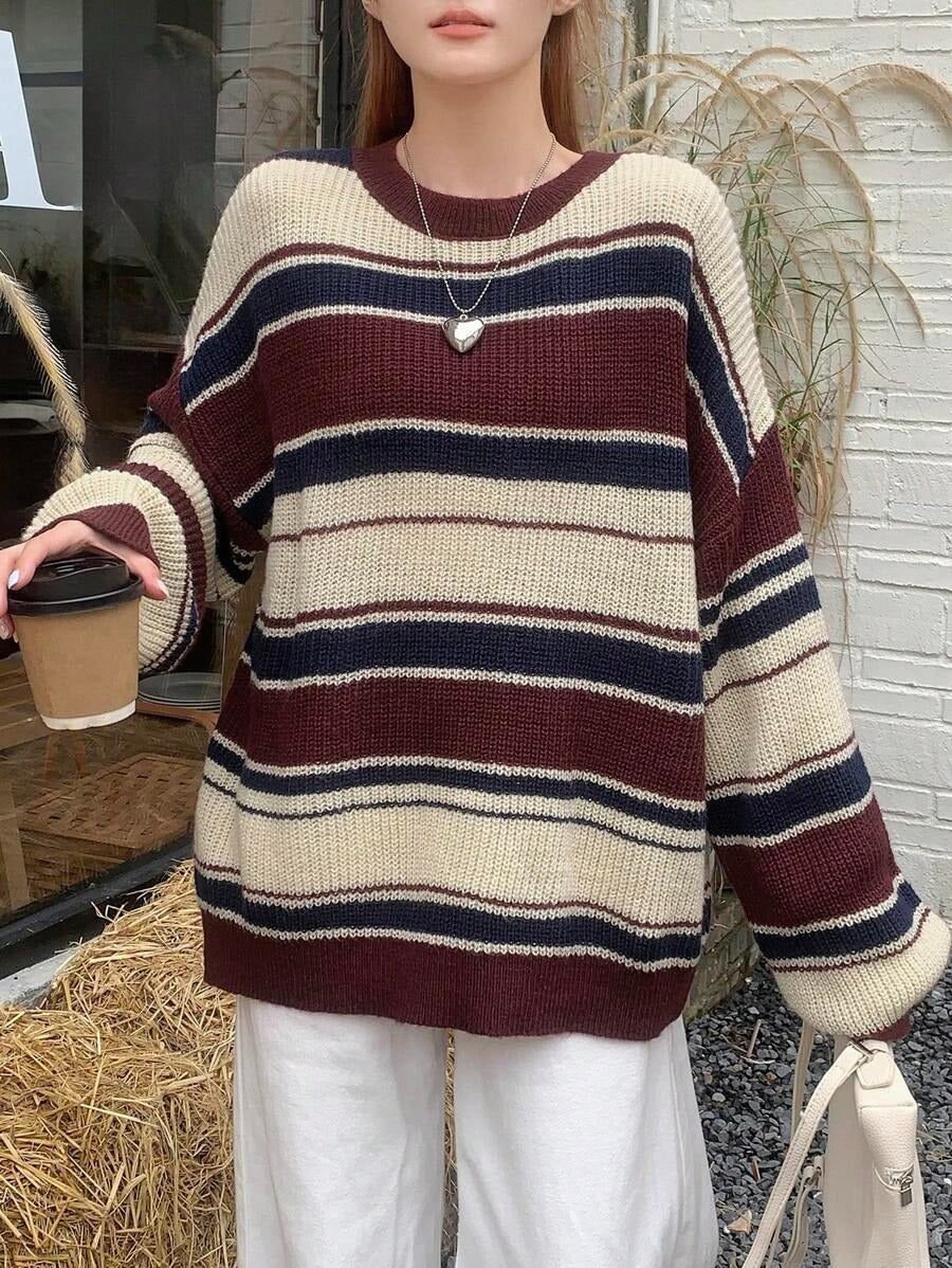 Person wearing a striped sweater holding a coffee cup outdoors.