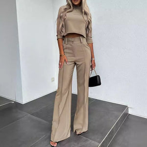 Woman wearing a beige outfit with high-waisted pants and a crop top in an indoor setting.