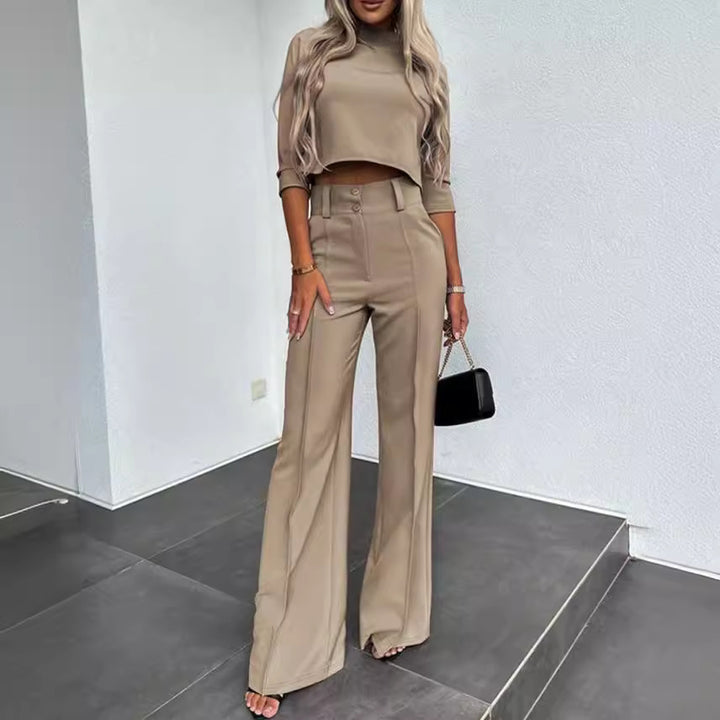Woman wearing a beige outfit with high-waisted pants and a crop top in an indoor setting.