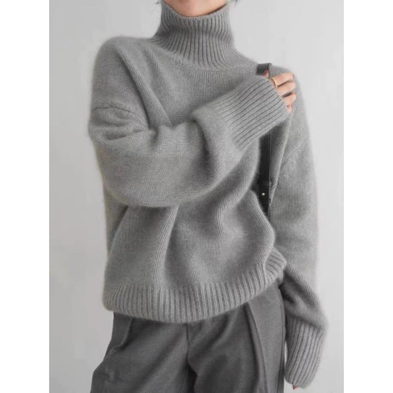 Person wearing a gray turtleneck sweater against a plain background