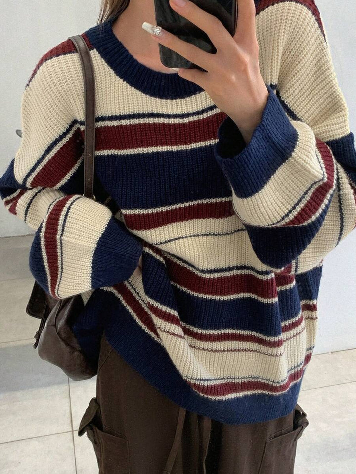 Person wearing a striped sweater with blue, red, and beige colors.