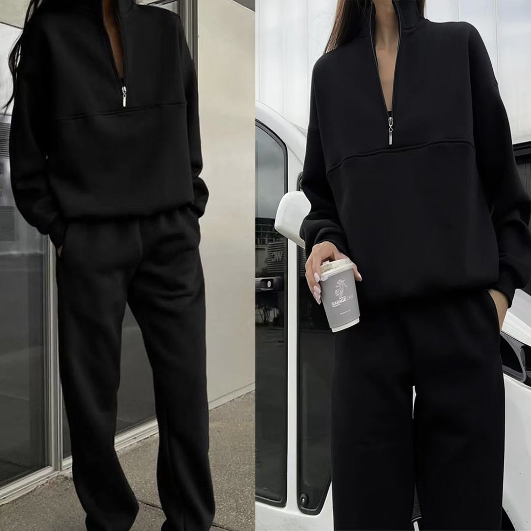 Person wearing a black tracksuit holding a coffee cup in an urban setting.