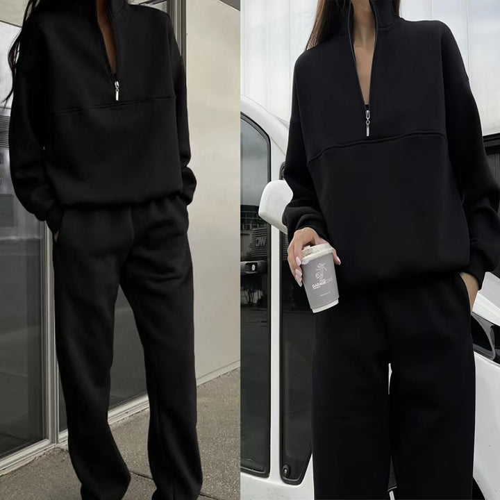 Person wearing a black tracksuit holding a coffee cup in an urban setting.