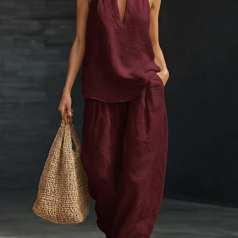 Person wearing a burgundy outfit holding a woven bag against a dark background
