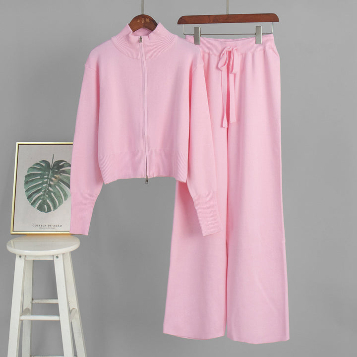 Pink tracksuit on hangers with a plant-themed picture frame in the background